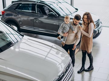 Eine Familie erkundet bei Autoankauf Hildesheim und bewundert ein weißes Fahrzeug, während ein stilvoller SUV im Hintergrund in einem modernen Showroom zu sehen ist.