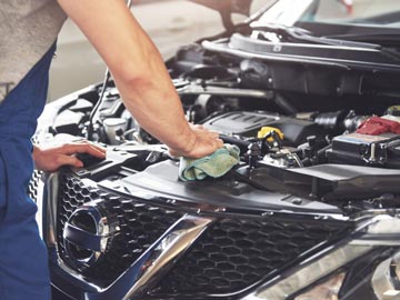 Motorschaden Ankauf in Hildesheim – Wir kaufen Autos in jedem Zustand Ein Mechaniker wischt den Motor eines Nissan-Autos ab und konzentriert sich auf die Wartung in einer gut beleuchteten Garage.