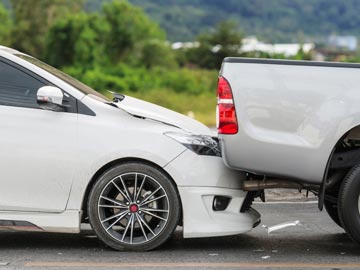 Unfallwagen Ankauf in Hildesheim – Schnell, fair und unkompliziert Ein weißer Sedan wird von einem silbernen Pickup auf einer Straße aufgefahren, wobei der vordere Teil des Sedans sichtbare Schäden aufweist.